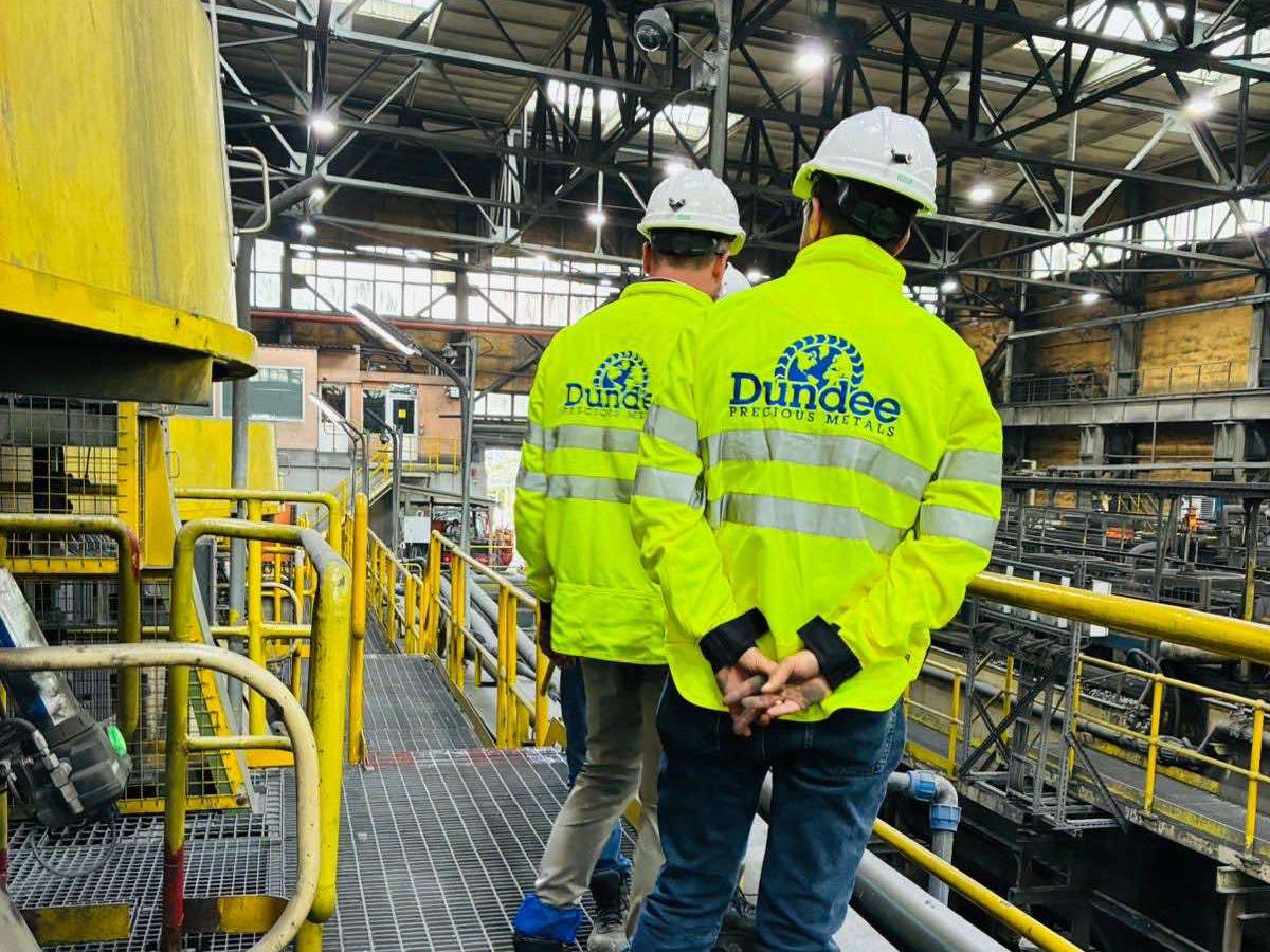 Двама посетители в светлоотразителни якета на Dundee Precious Metals на пътека до мелницата в ДПМ България